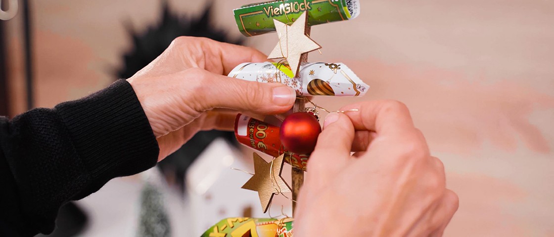 Zwei Hände verzieren mit Weihnachts-Deko | DIY-Idee Tannenbaum