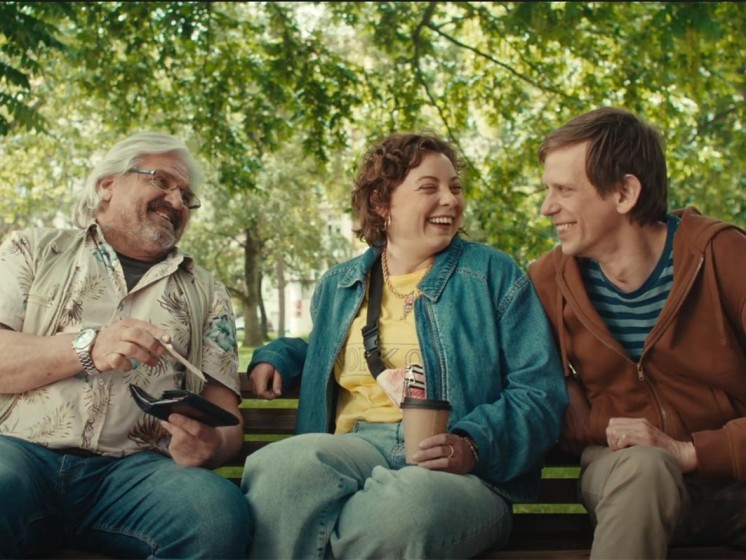 Drei Menschen aus NRW sitzen auf einer Parkbank und lachen | WestLotto